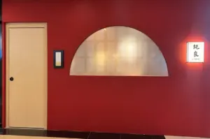Red restaurant entrance with a light wood door, arched frosted window, and illuminated Junryo sign.