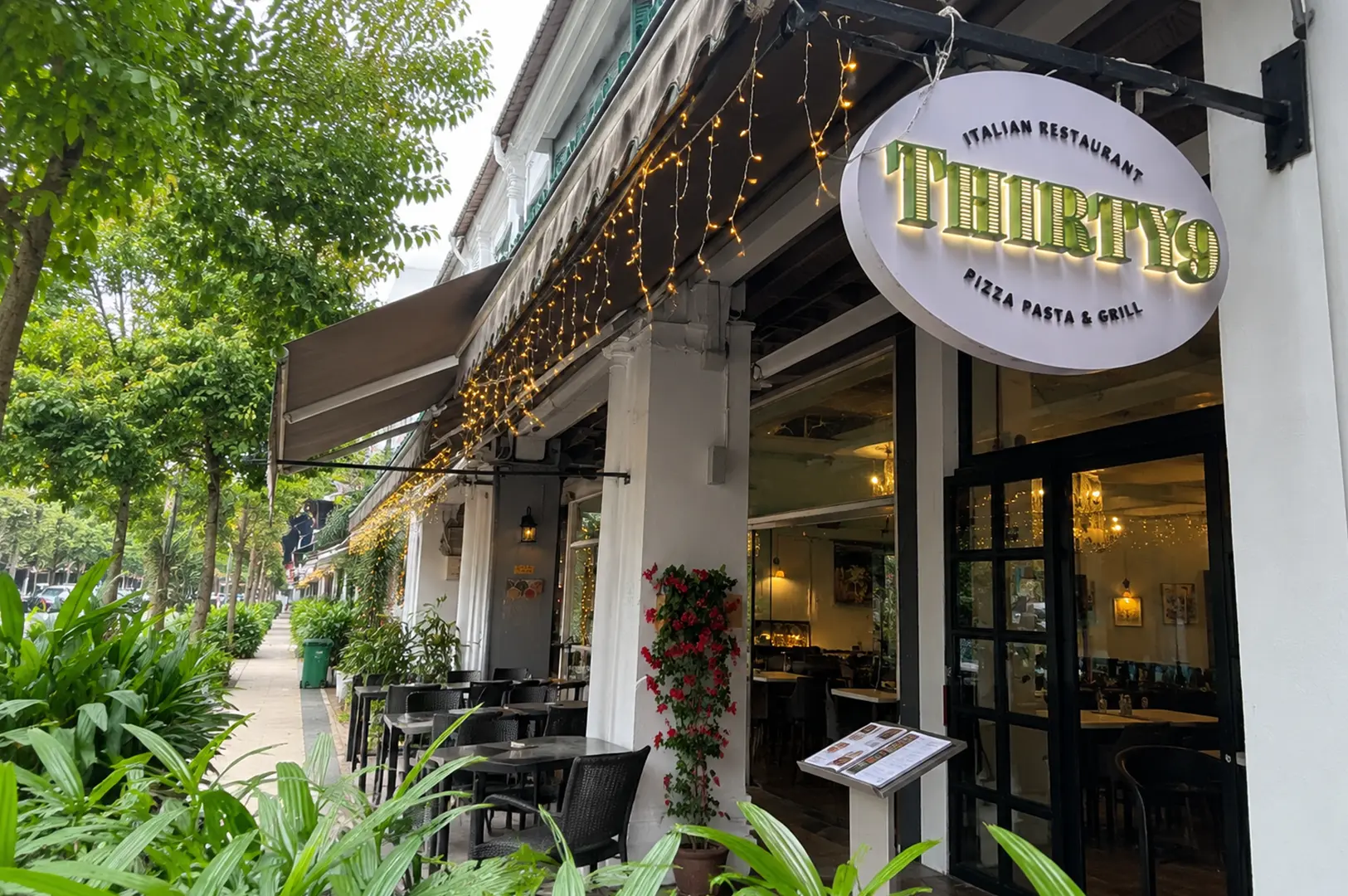 Exterior of Thirty9 Italian Restaurant with outdoor seating, greenery, and warm string lights.