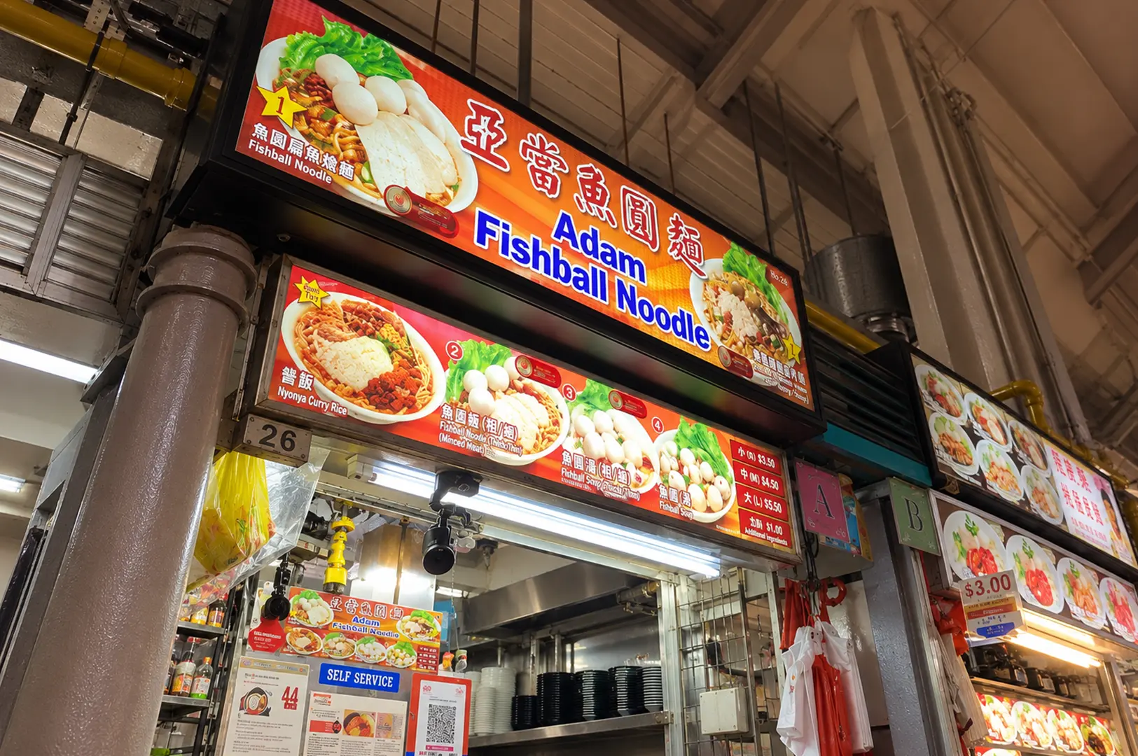 Adam Fishball Noodle stall with colorful menu boards showcasing fishball noodles, curry rice, and noodle variations.