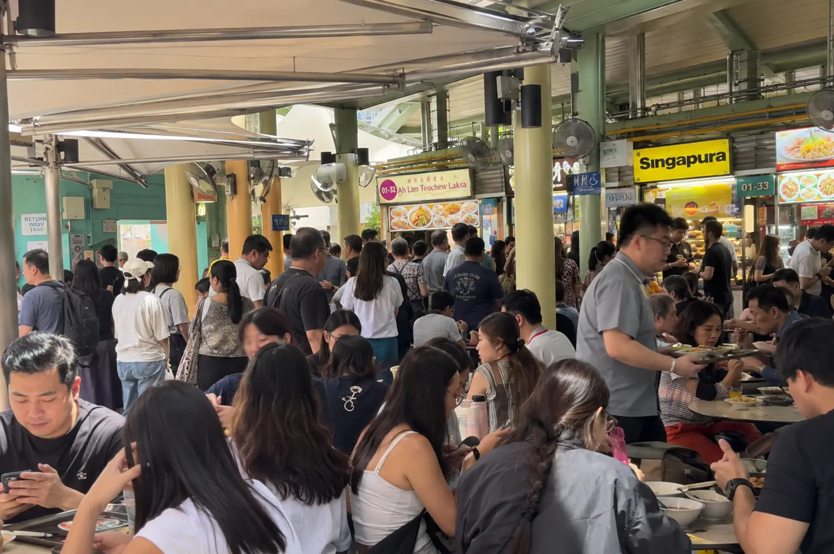 A crowded Singapore hawker centre filled with diners, food stalls, and many choices.