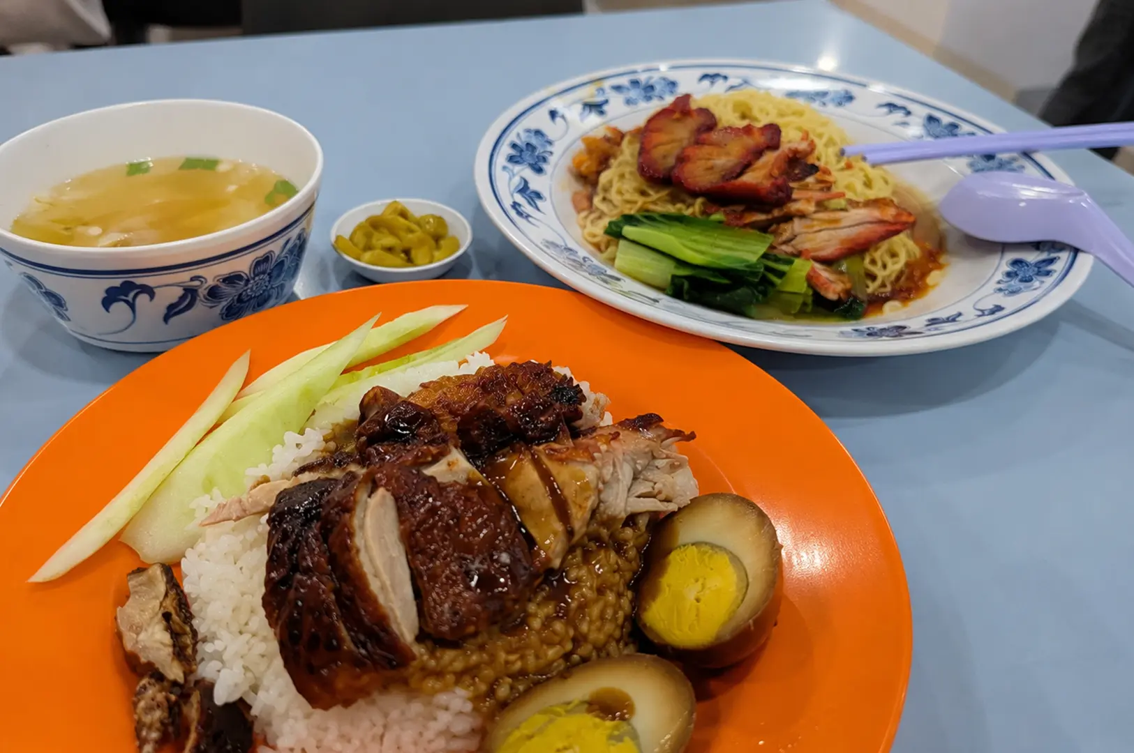 Roast chicken rice and char siu noodles served with soup, pickled chilies, and soy eggs.