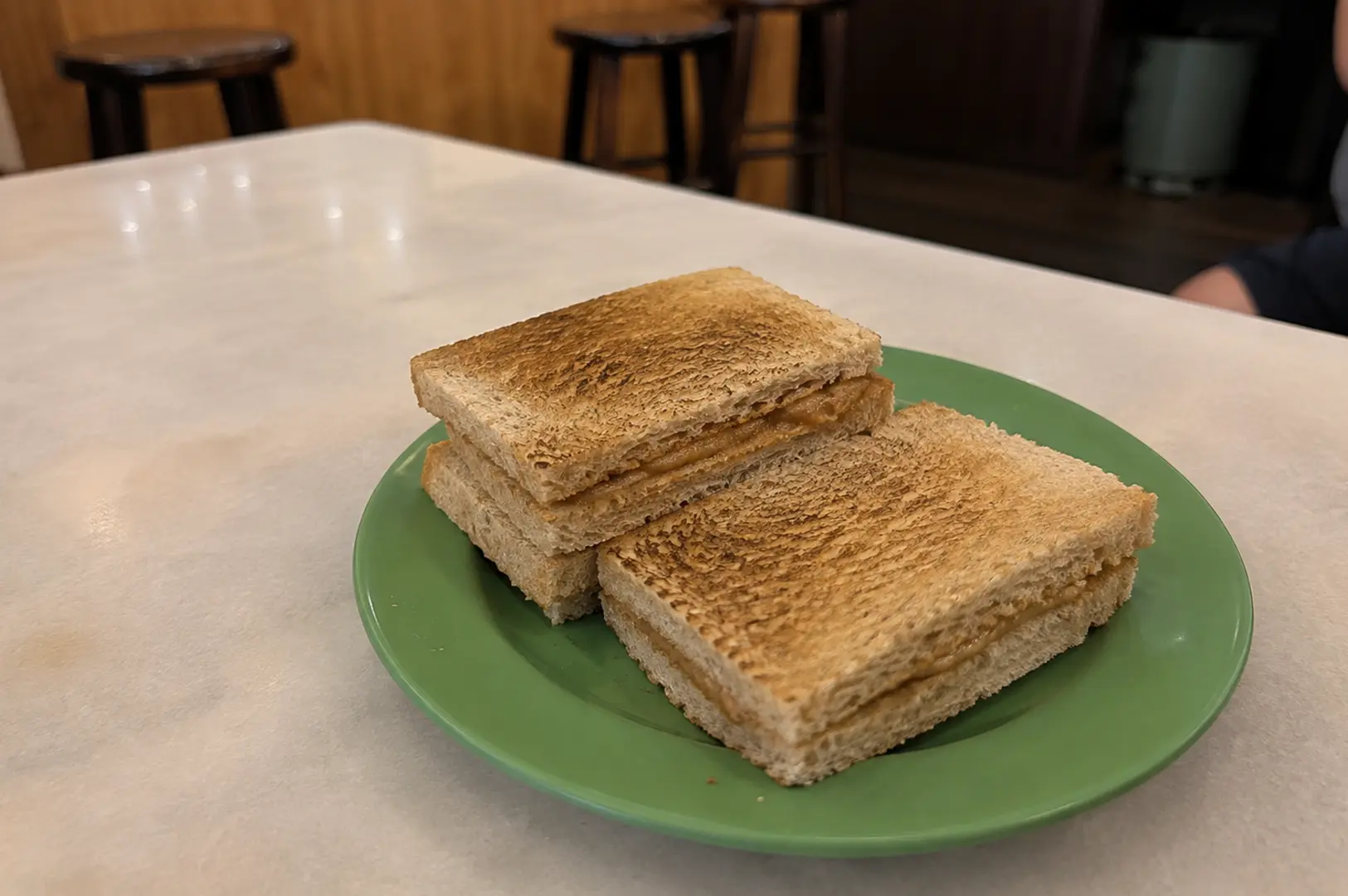 Crispy Singapore kaya toast served on a green plate at a traditional kopitiam.