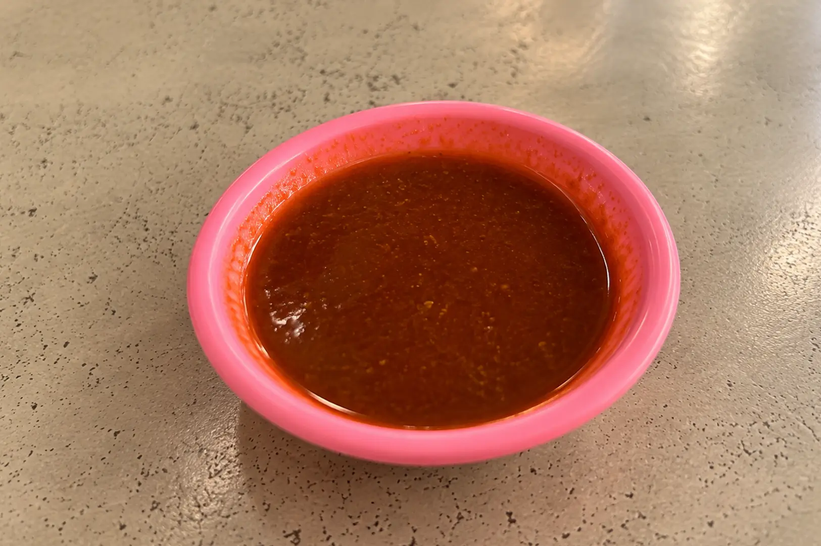 Close-up of the sweet and spicy dipping sauce served alongside Hup Kee Fried Oyster Omelette on a pink plastic dish