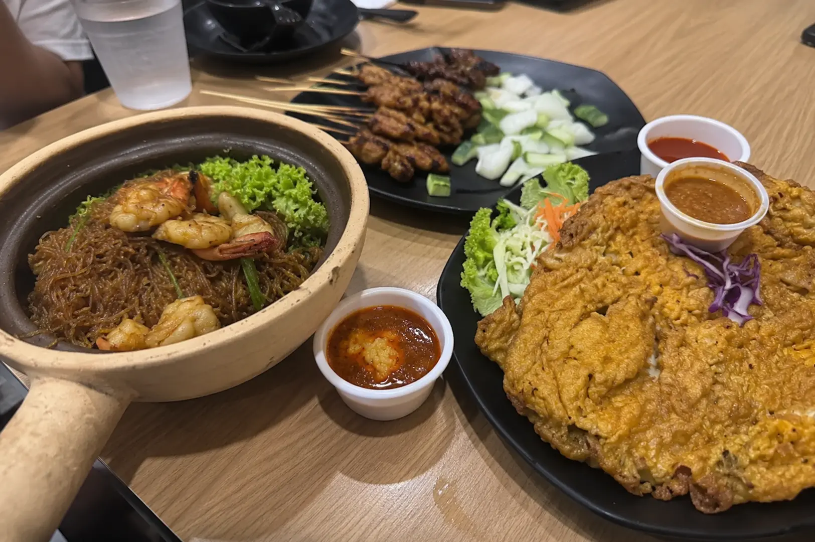 Claypot glass noodles, satay skewers, and crispy fried omelette served with dipping sauces.