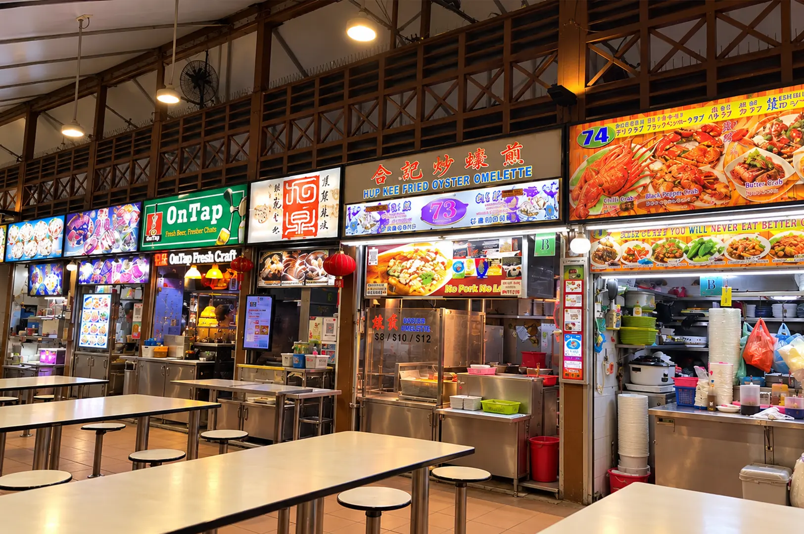 Hup Kee Fried Oyster Omelette stall and open seating area inside a busy Singapore food centre, surrounded by neighboring food stalls