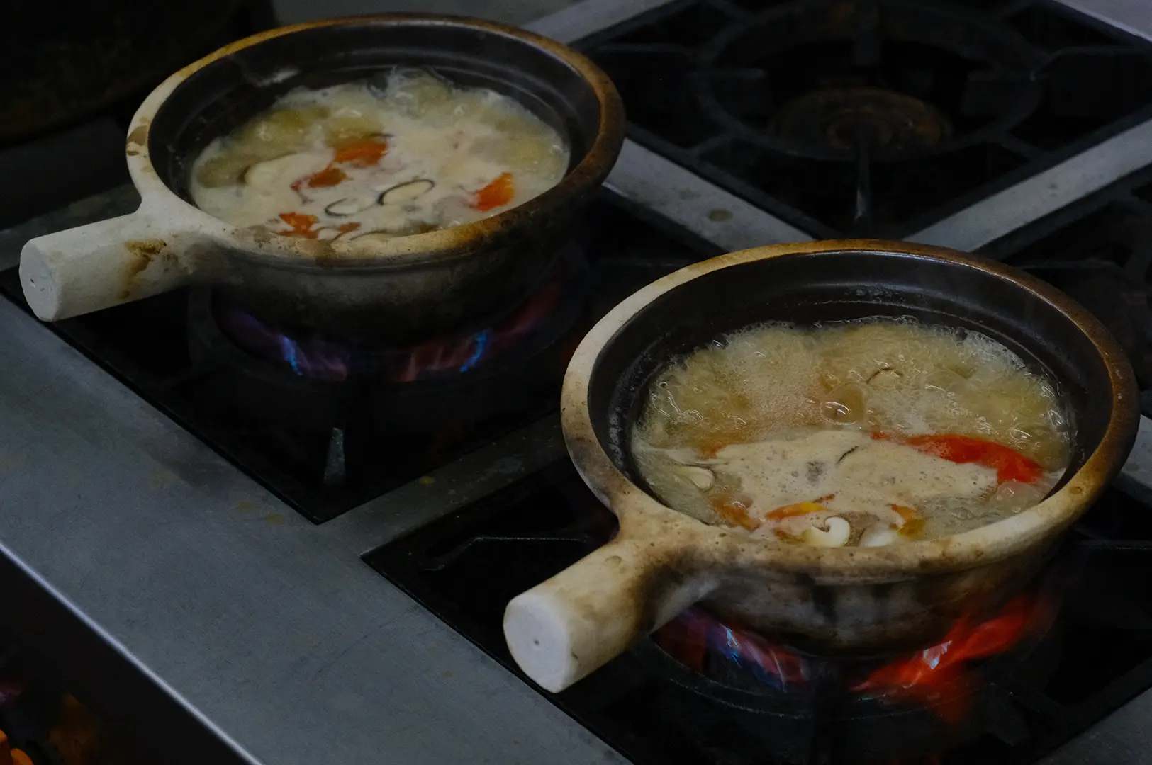 Clay pots of seafood soup simmering over open flames in Hup Lok’s kitchen.