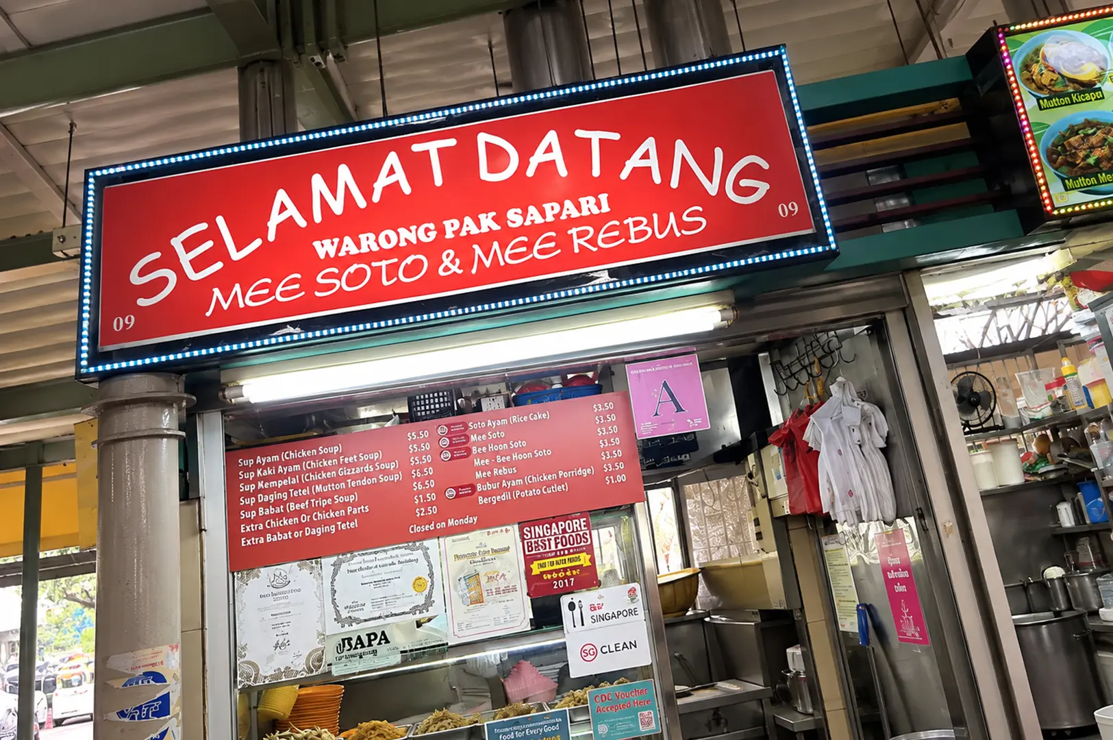Warong Pak Sapari stall with its bright red sign and menu featuring mee soto and mee rebus.
