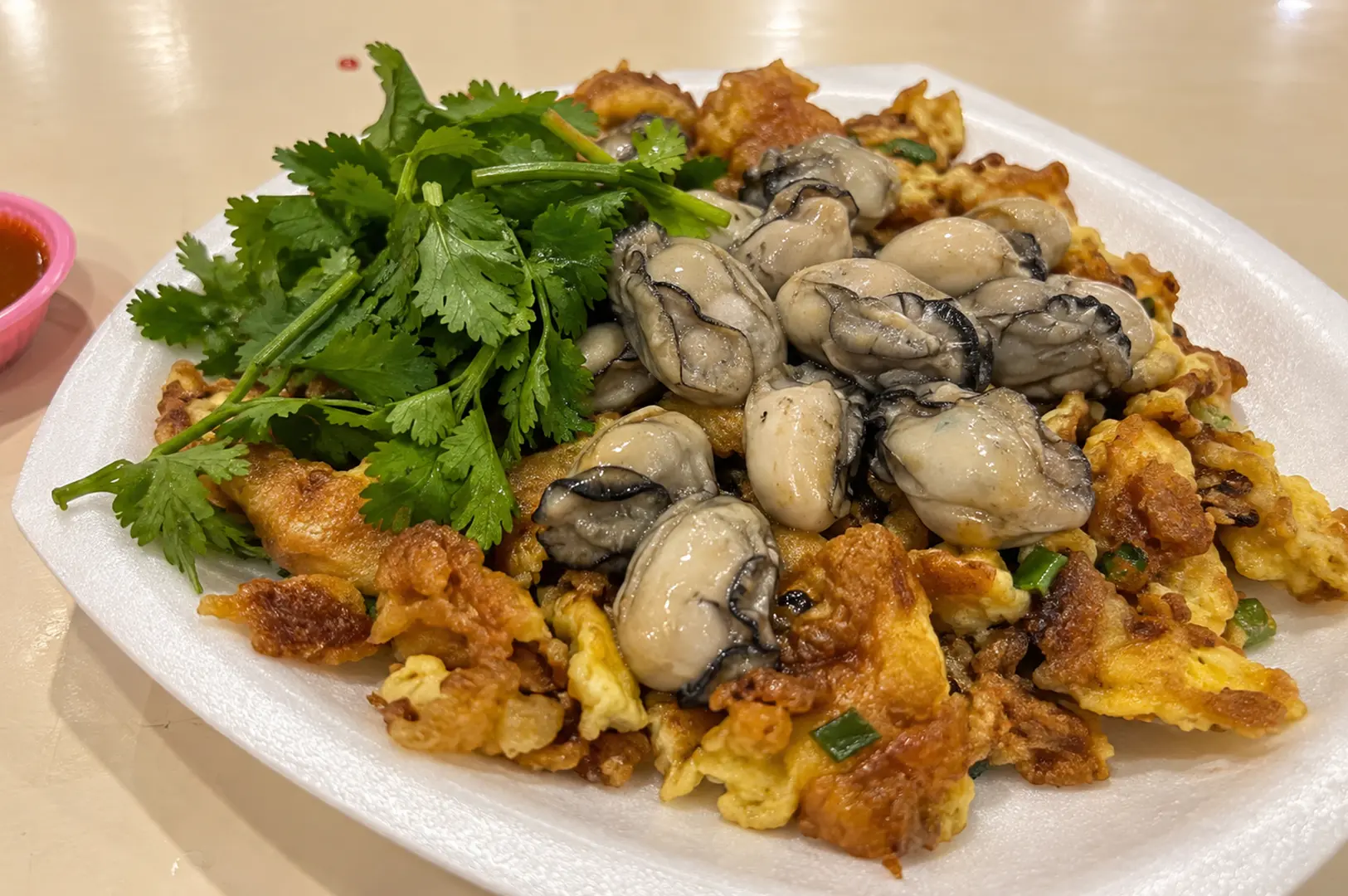 Close-up of Hup Kee Fried Oyster Omelette with plump oysters, crispy golden egg batter, spring onions, and fresh coriander
