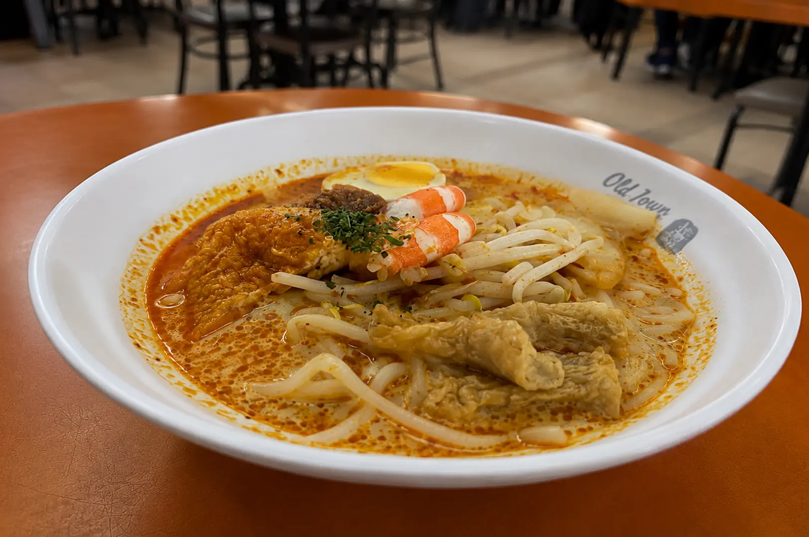 Spicy laksa topped with prawns, tofu puffs, egg, and bean sprouts in rich broth.
