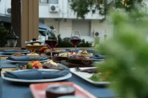 An elegant outdoor dining table set with multiple dishes, wine glasses, and neatly arranged plates.