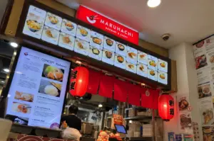 Maruhachi Donburi & Curry stall featuring its illuminated red sign, menu boards, and traditional Japanese-inspired décor.