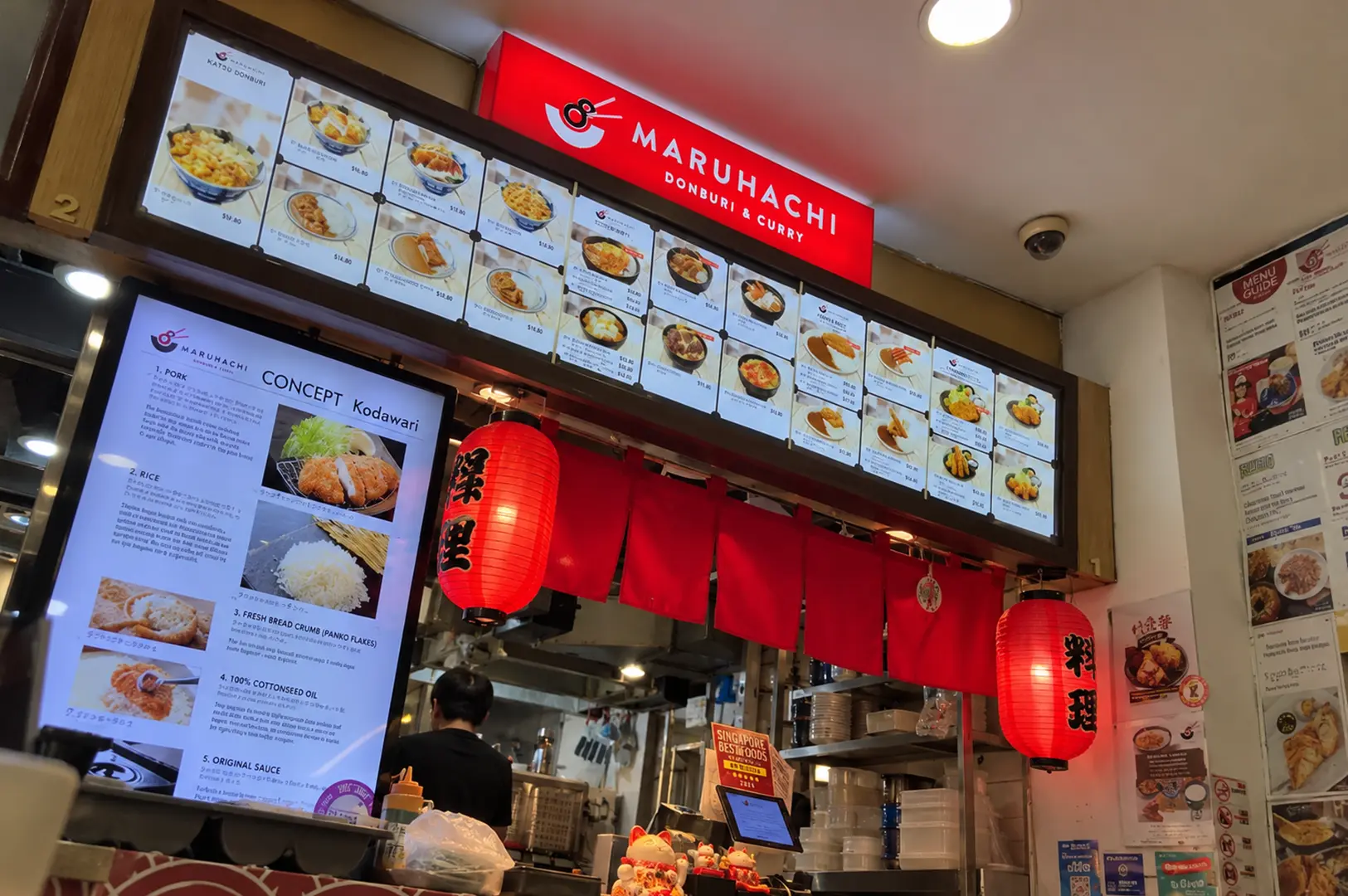 Maruhachi Donburi & Curry stall featuring its illuminated red sign, menu boards, and traditional Japanese-inspired décor.