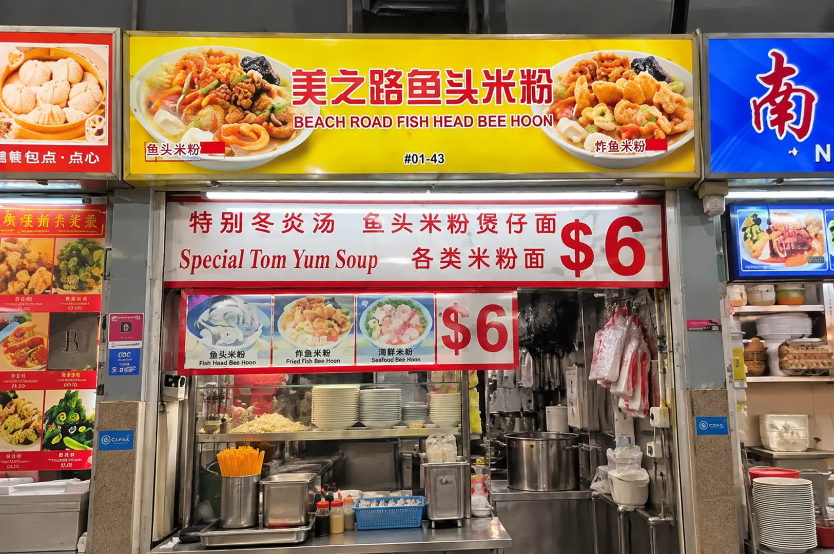 Beach Road Fish Head Bee Hoon stall with bright yellow signage, menu boards, and an open kitchen counter.