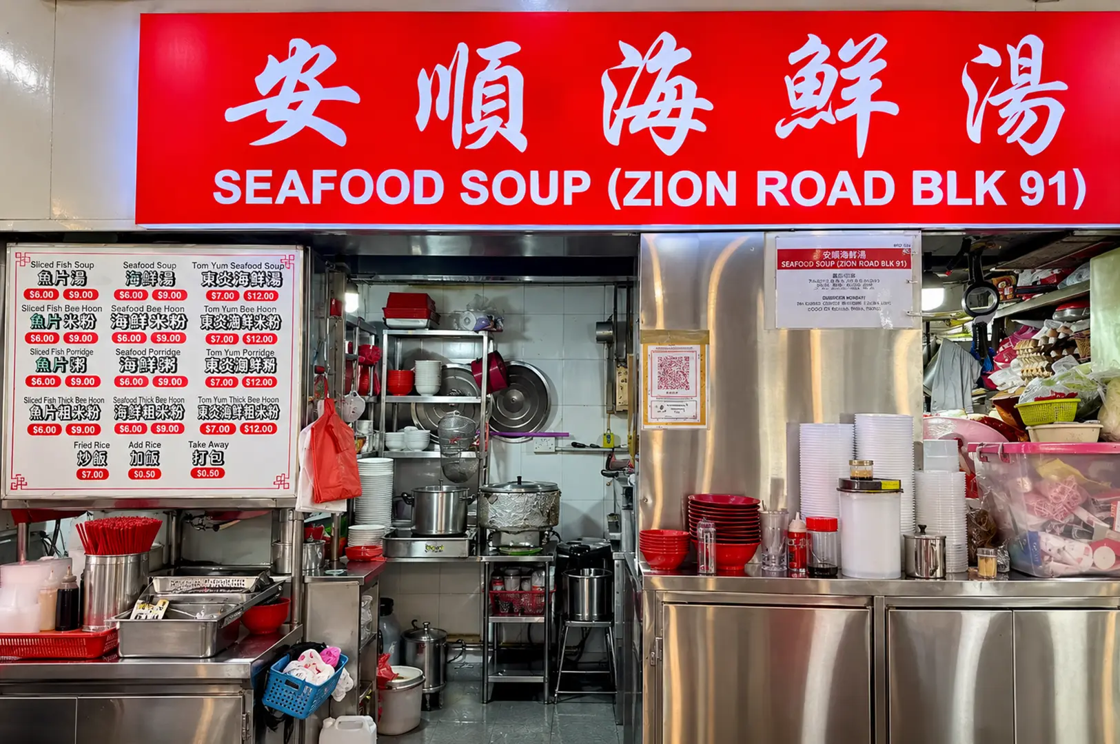 Seafood Soup stall with a bright red sign, menu board, stainless steel counter, and busy open kitchen.