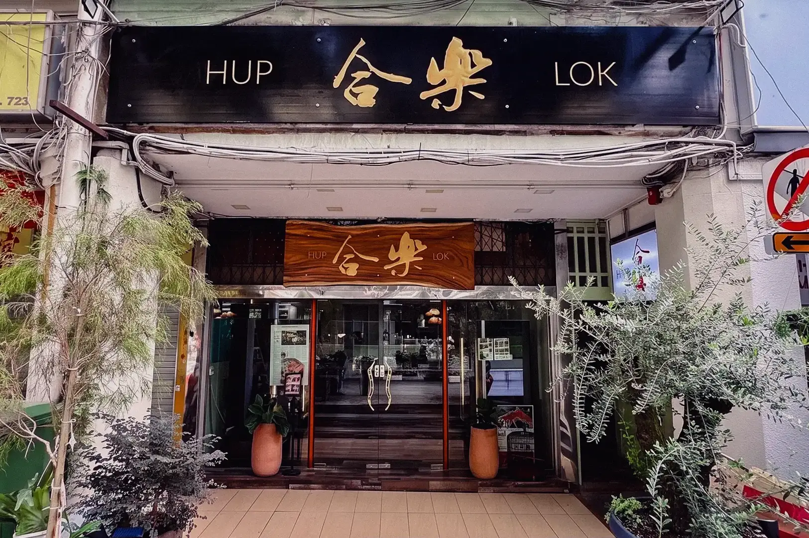 Exterior view of Hup Lok restaurant with its traditional Chinese sign and greenery surrounding the entrance.