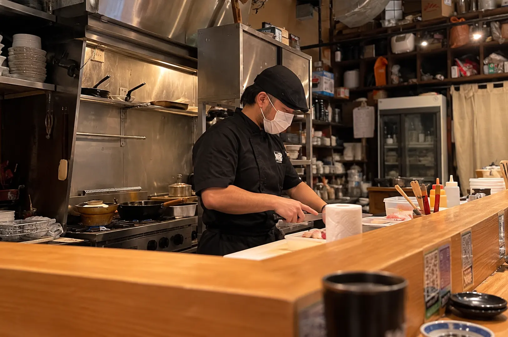 Chef preparing food behind the wooden counter at Teppei Japanese Restaurant in Singapore.