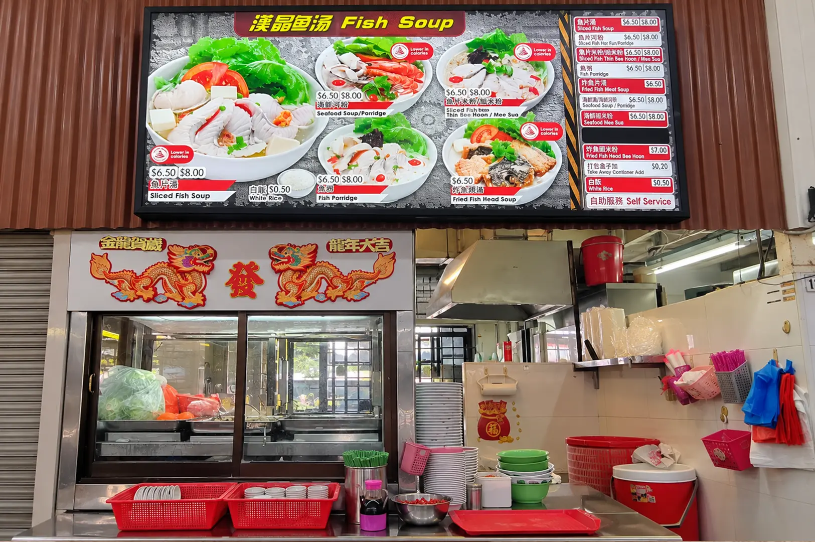 Fish soup stall with a large menu board displaying sliced fish soup and other seafood dishes.