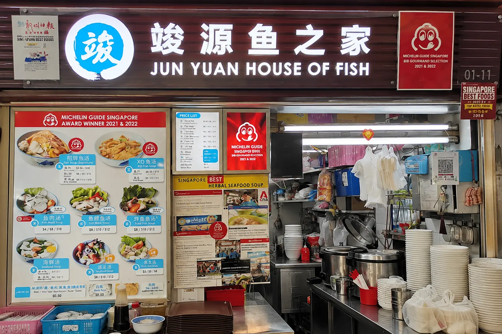 Jun Yuan House of Fish stall featuring its large sign, seafood soup menu, Michelin Guide awards, and open kitchen.