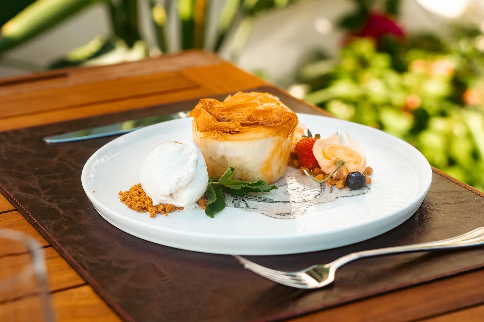 An elegant plated pastry dessert accompanied by ice cream, fresh berries, and decorative garnishes.