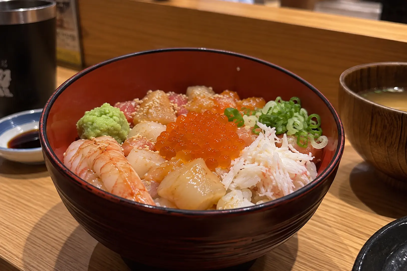 Close-up of Teppei's seafood chirashi bowl topped with salmon, scallops, shrimp, crab, ikura, and wasabi.