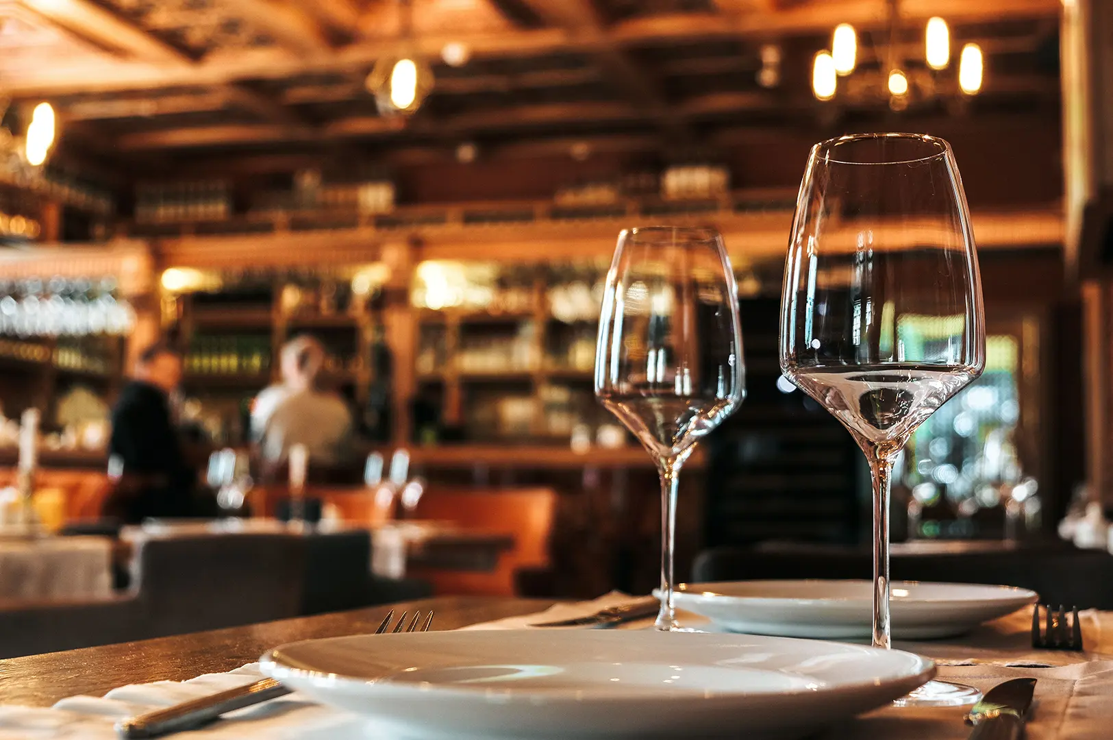 A sophisticated restaurant table featuring white plates, polished cutlery, and wine glasses.