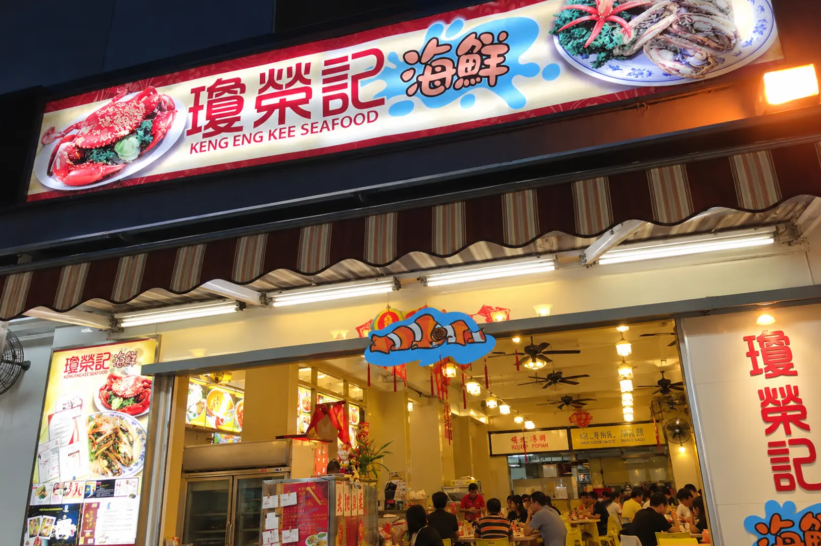 Keng Eng Kee Seafood restaurant exterior with a brightly lit sign and a busy dining area.