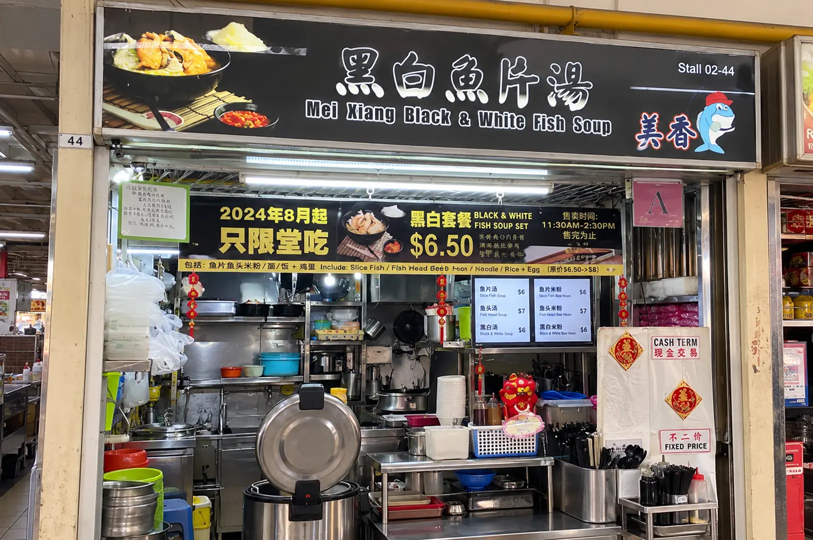 Mei Xiang Black & White Fish Soup stall with its black signboard, menu, and open kitchen counter.